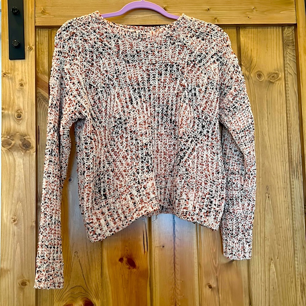 Knit sweater made out of 100% polyester. Is a mix of pink, red and creme